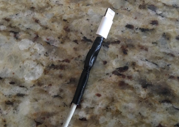 A repaired broken iPhone charger temporarily fixed with electrical tape